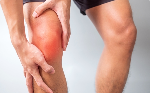 A person holding a knee that is red with pain