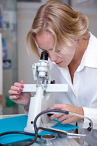 lab worker looking into microscope